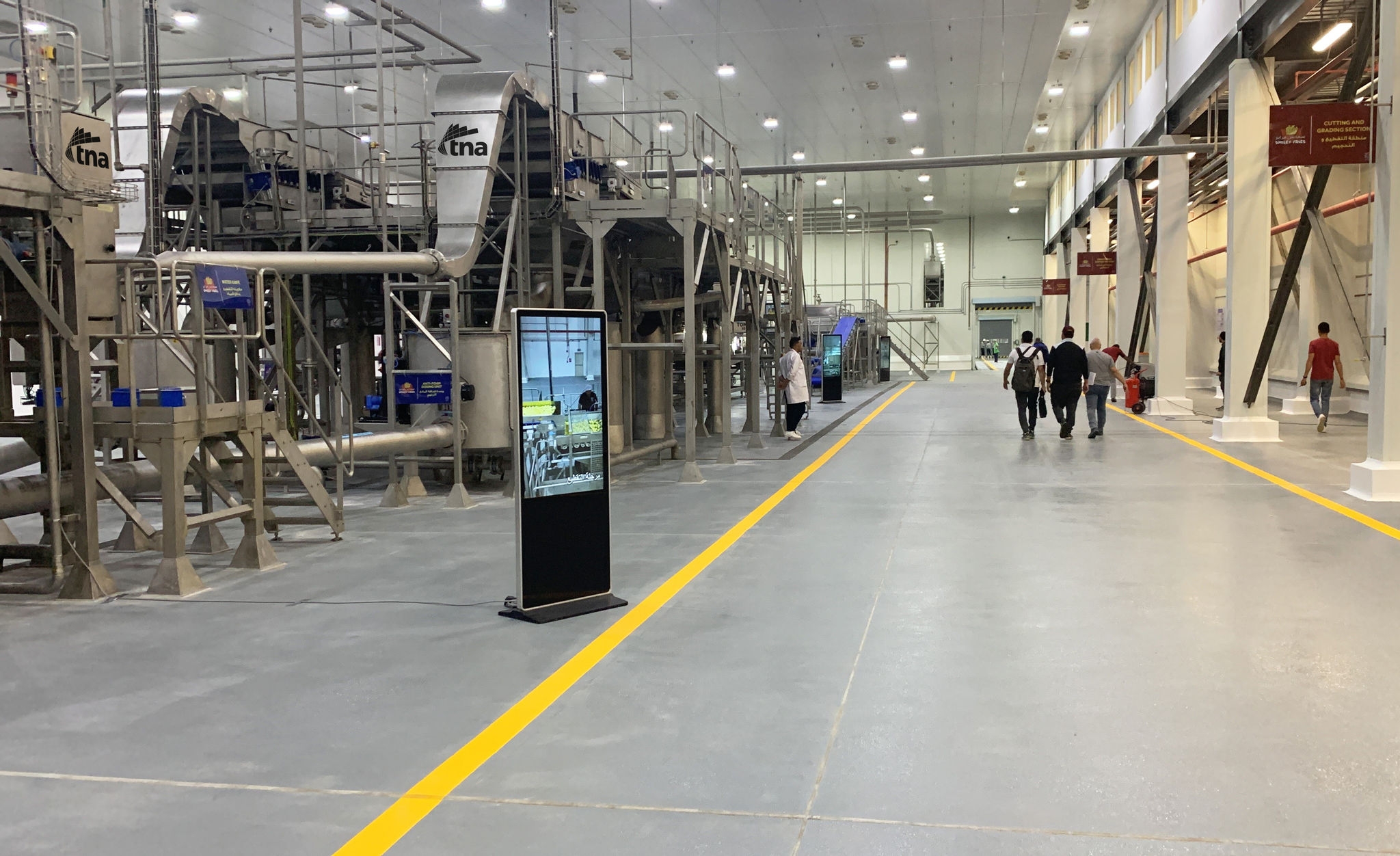 inside a factory with a yellow line on the floor and lights in the ceiling 