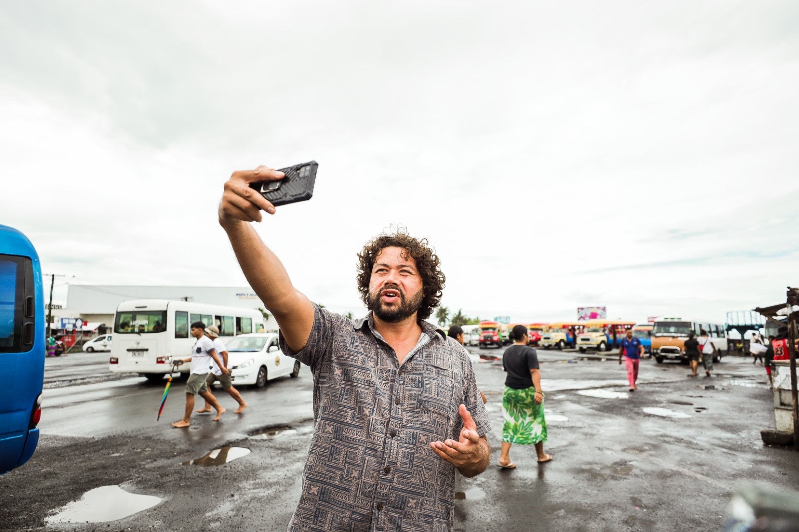 person taking a selife in a street with a bus in background