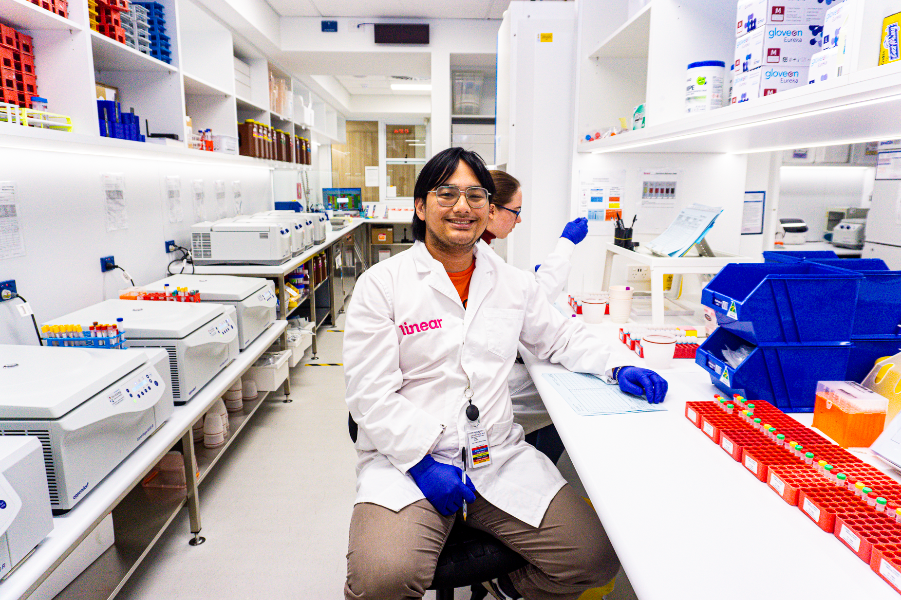 Man sitting in a lab smiling, wearing a lab coat