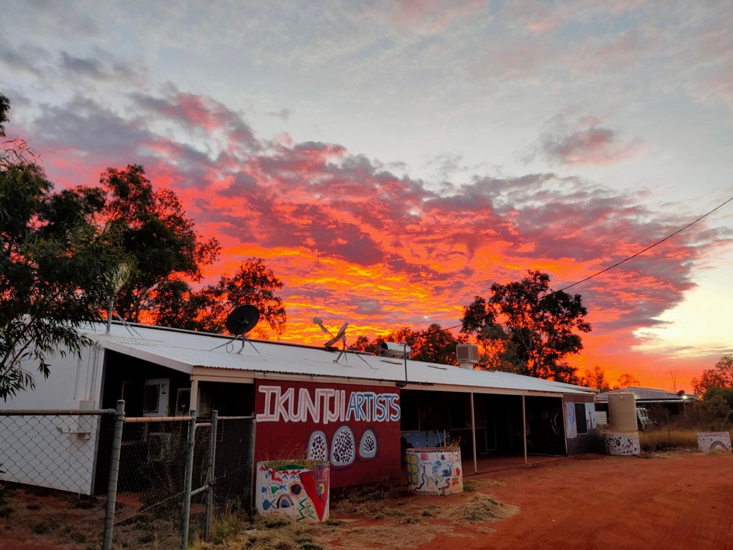 white building with a red sign with large writing. sunset background