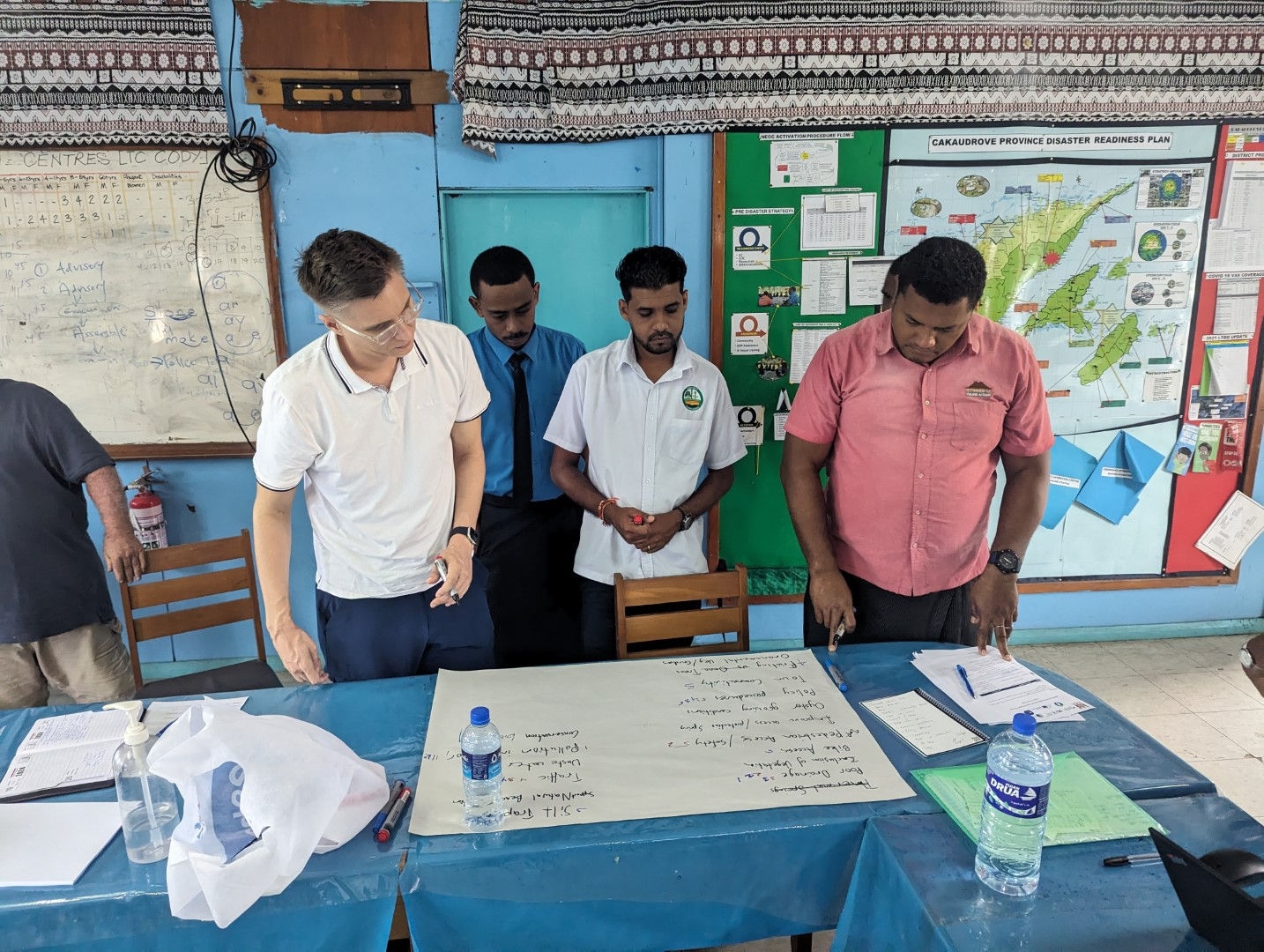 people standing around a blue table with a white poster