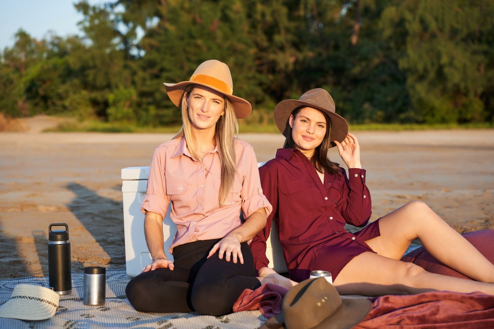 two people sitting on beach with blankets 