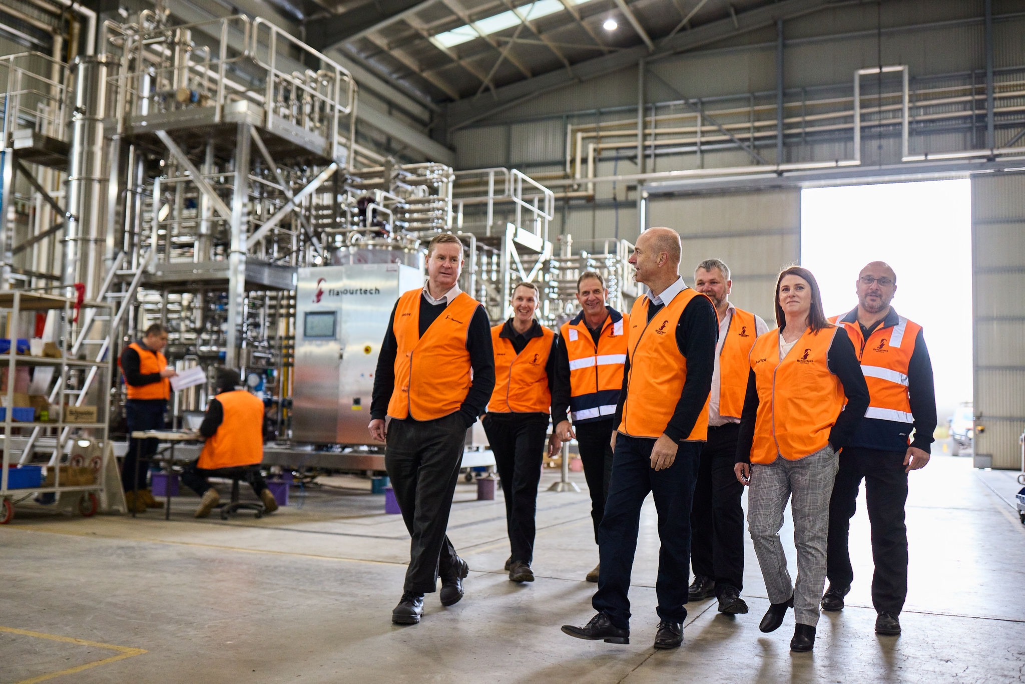 group of people walking in a factory in high vis