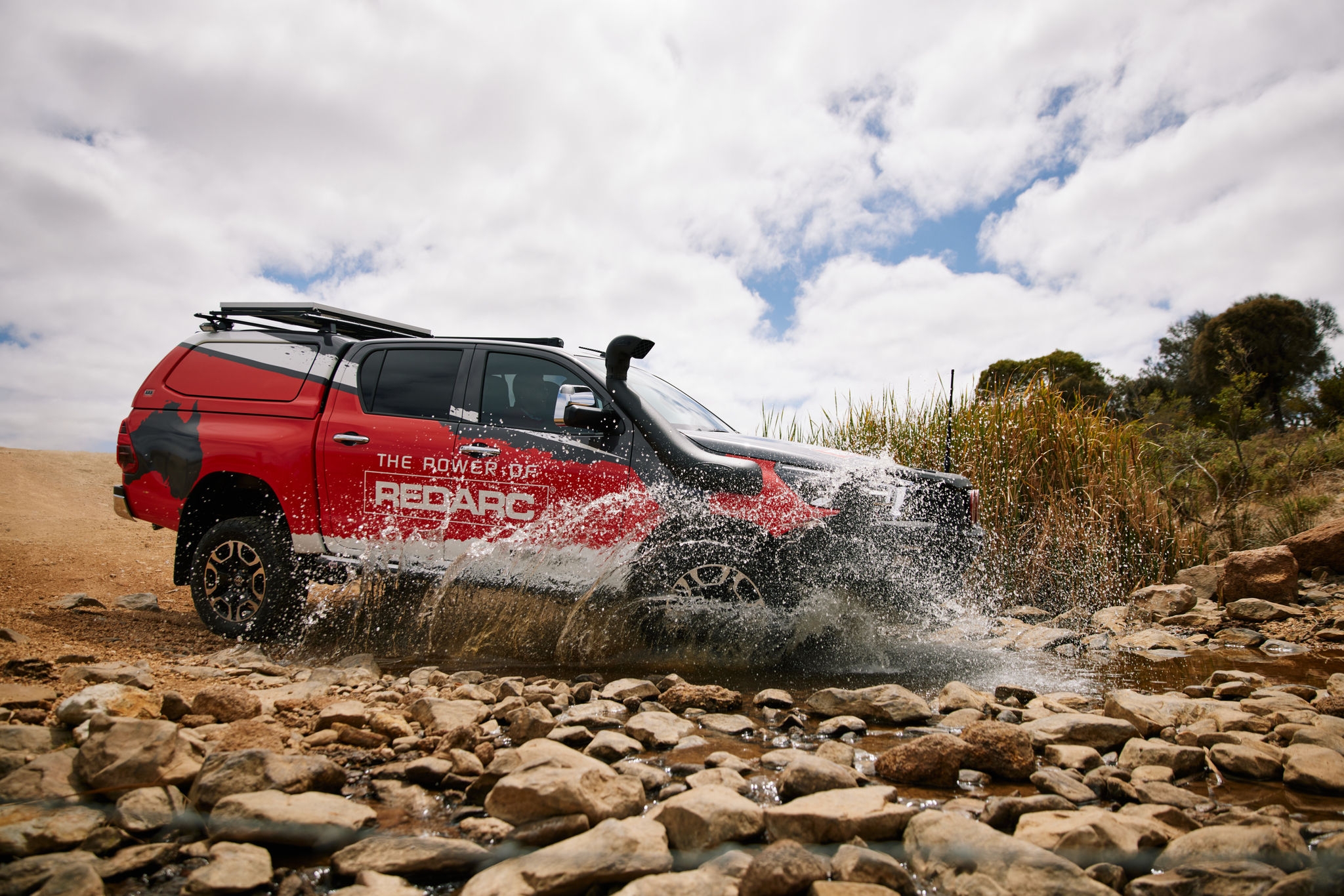 red 4x4 car driving through a puddle