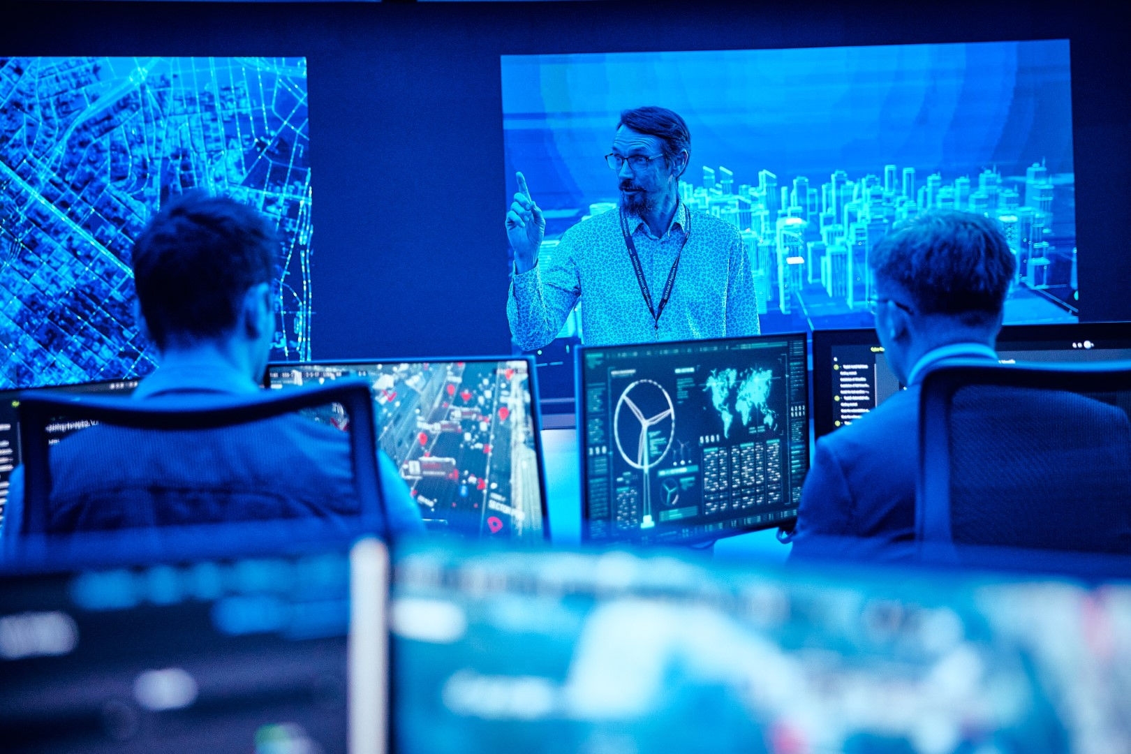 a blue classroom with a teacher and two students behind a screen 